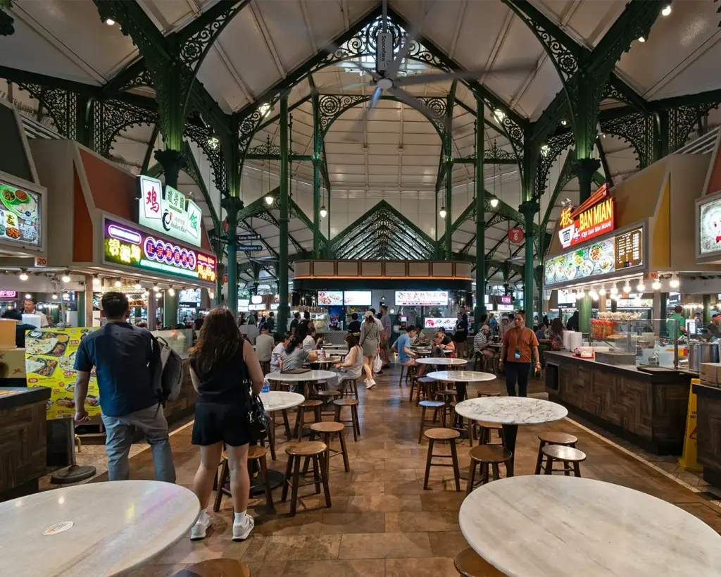 A vibrant Singapore hawker centre filled with food stalls and diners enjoying affordable local dishes, capturing the lively atmosphere of the city’s iconic communal dining culture.