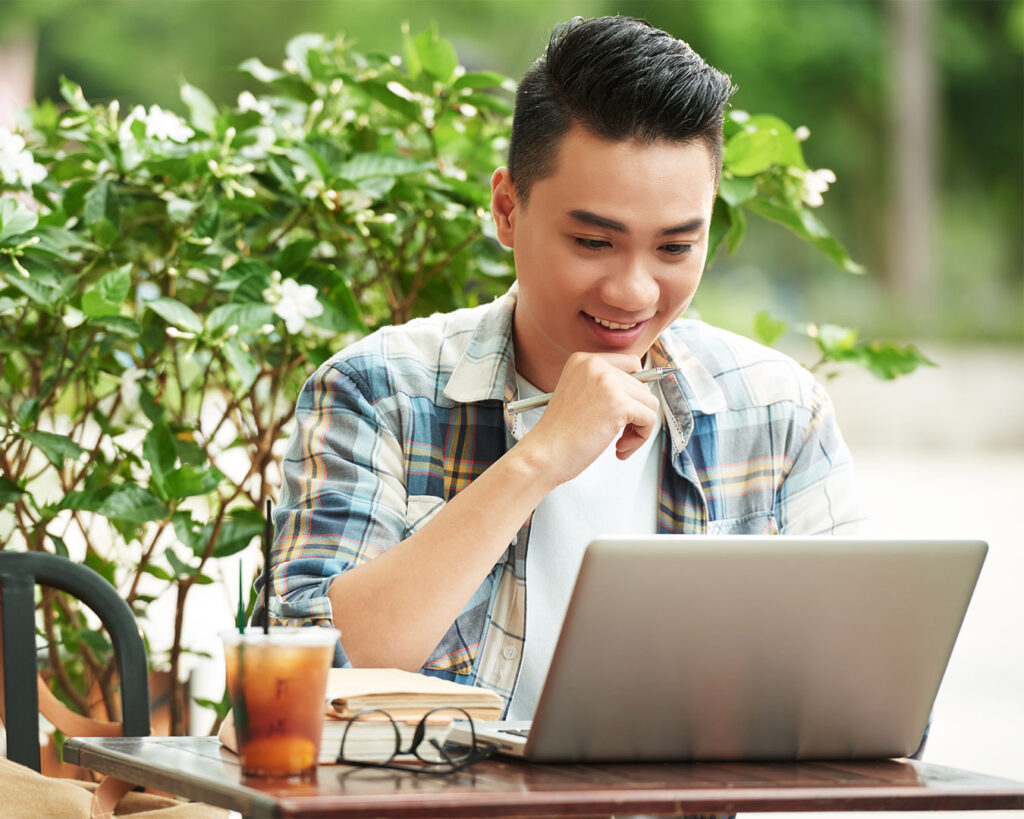 A man seated with his laptop on a table, concentrating on his work in a casual office or home setting.