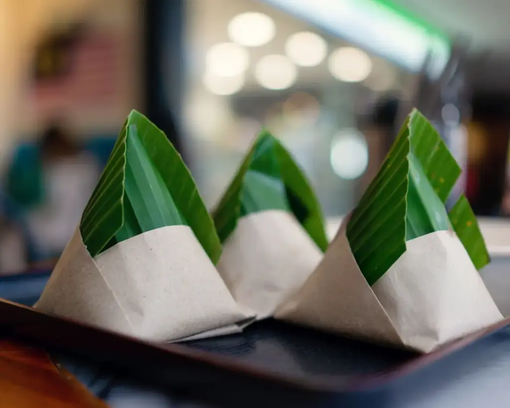 Traditional nasi lemak wrapped in banana leaf packaging, a popular Malaysian breakfast dish known for its fragrant coconut rice and spicy sambal.