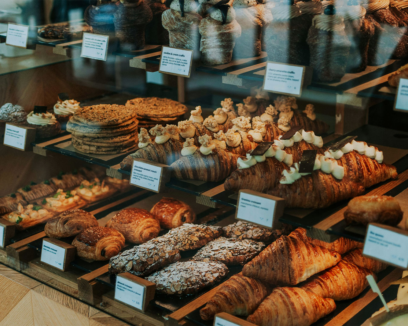 An assortment of pastries arranged neatly inside a glass display case, including croissants and cakes, showcasing a fresh and inviting bakery selection.